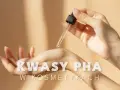 Kropla serum z kwasami PHA spada na dłoń, symbolizując delikatną pielęgnację.