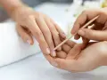 Delikatne dłonie poddawane zabiegowi manicure biologicznego. Skórki są starannie odsuwane patyczkiem.