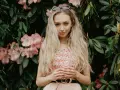 Blondynka w kwiecistej sukience, z okularami na głowie, otoczona różowymi kwiatami rododendronów. To kwintesencja słowiańskiej urody.