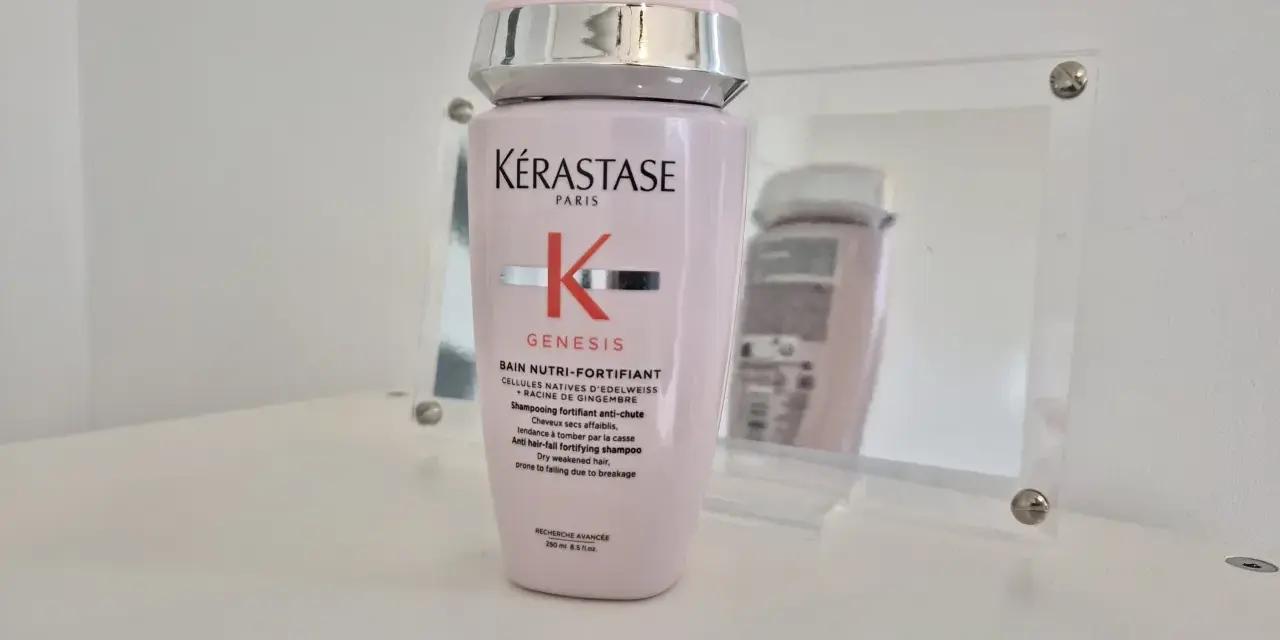 Różowa butelka szamponu Kérastase Genesis, odbijająca się w lustrze.