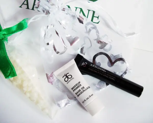 Arbonne opinie: zestaw kosmetyków z primerem i tuszem, w ozdobnym woreczku.