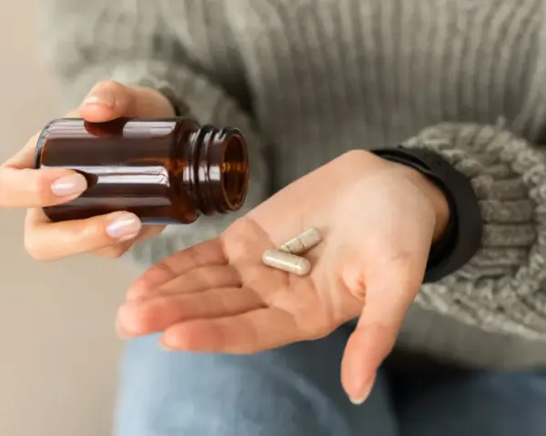 Dłoń z kapsułkami, zastanawiam się nad biotyna skutki uboczne.