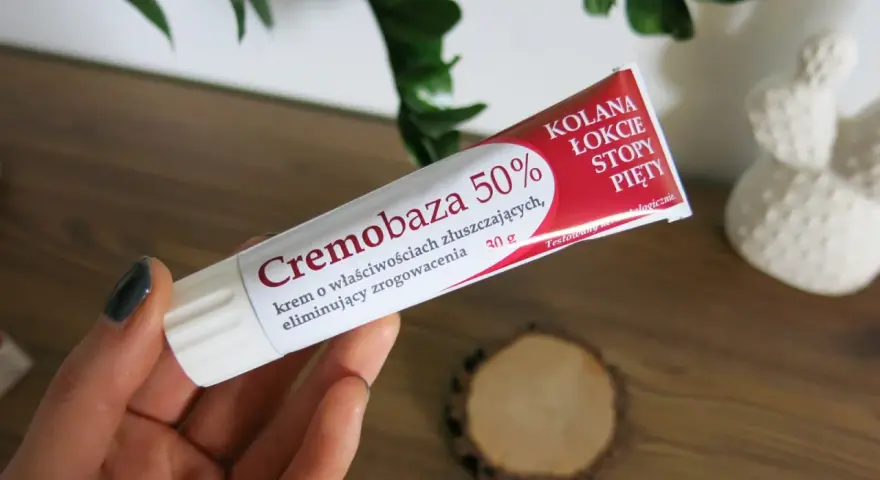 Dłoń trzyma tubkę kremu Cremobaza 50%, który pomaga na zrogowacenia. Brak informacji o skutkach ubocznych.