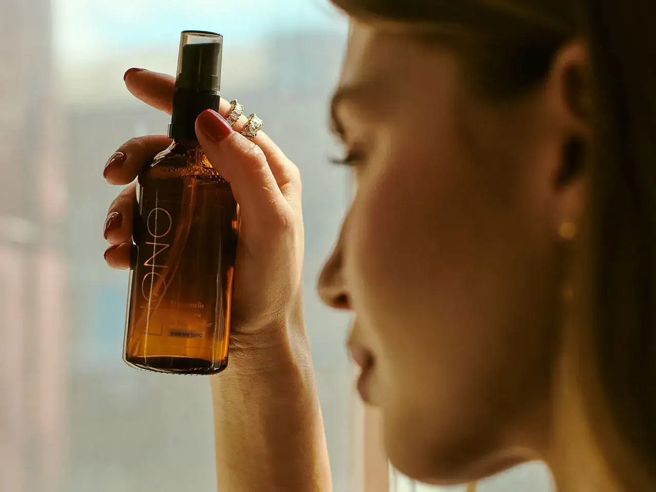 Kobieta trzyma buteleczkę z mgiełką, która zawiera m.in. cetearyl alcohol.
