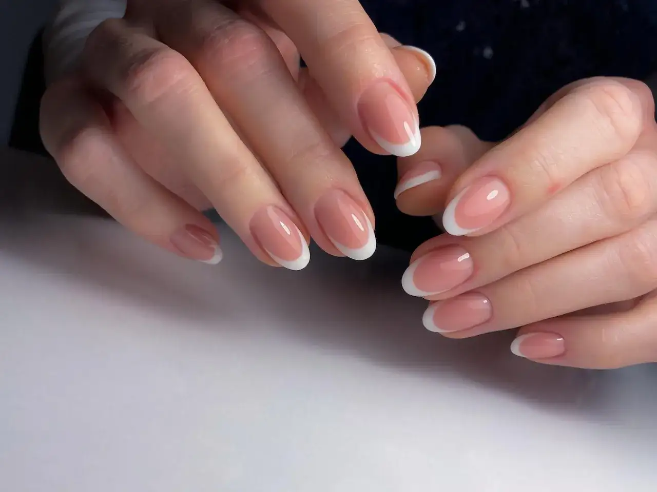 Dłonie z idealnym, krótki french manicure. Delikatny róż i biel podkreślają naturalne piękno paznokci.