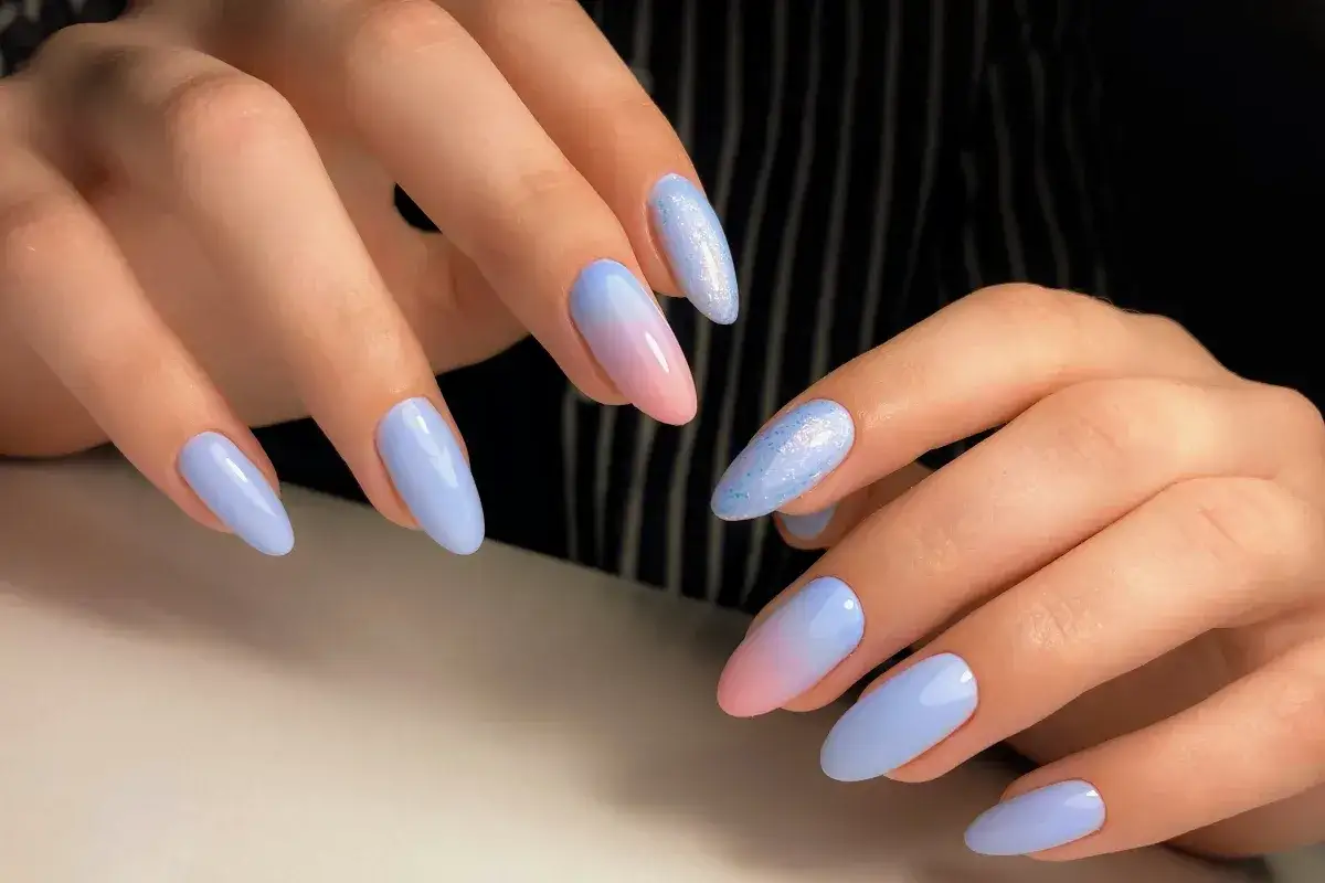 Delikatne baby boomer nails w odcieniach błękitu i różu, z brokatowym akcentem.